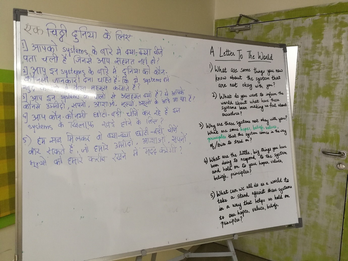 A whiteboard divided in two: on the left, prompts in Hindi (Devanagari script) titled 'एक चिट्ठी दुनिया के नाम'; on the right, the same prompts in English titled 'A Letter to the World'.